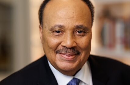 Martin Luther King the third in a suit coat and tie smiles posing for a portrait.